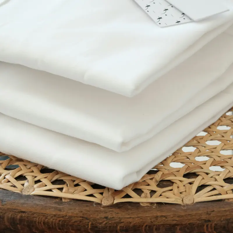 Draps blancs pliés au carré posés sur un cannage en rotin