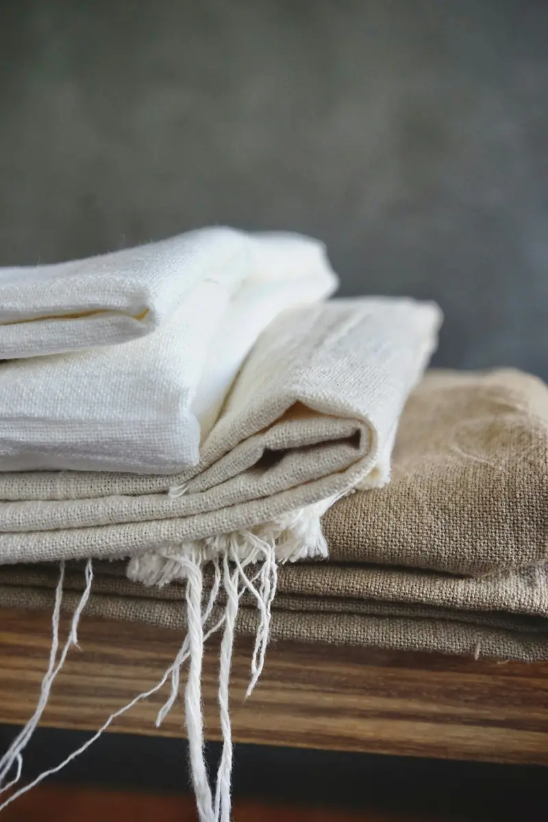 Pile de linge blanc et écru soigneusement plié sur une table d'atelier